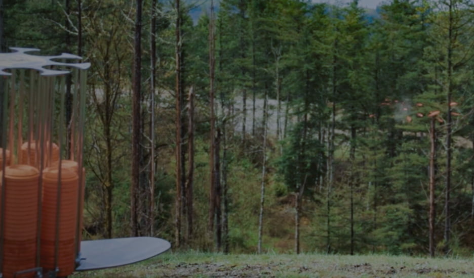 White Flyer targets being launched from a pitch machine against a wooded background