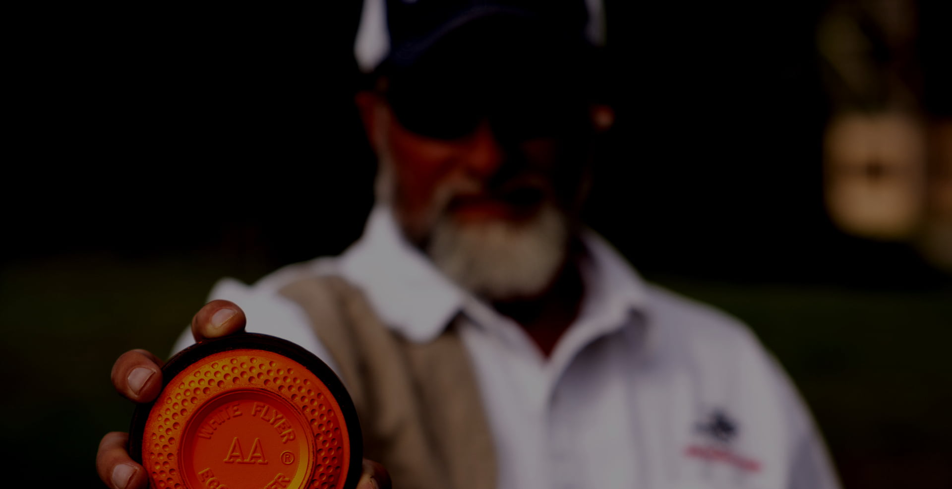 Man out-of-focus holding a White Flyer AA Eco Flyer target with dark overlay